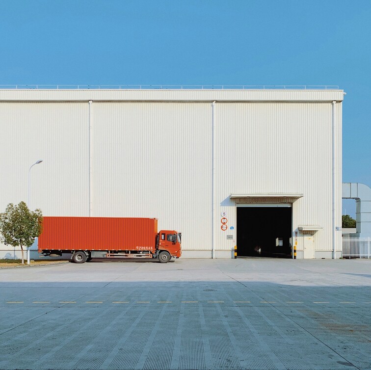 A delivery truck parked outside a warehouse, representing the local door-to-door delivery service of a load dispatching company that offers logistics solutions.